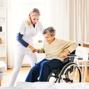 caregiver assisting senior woman in wheelchair